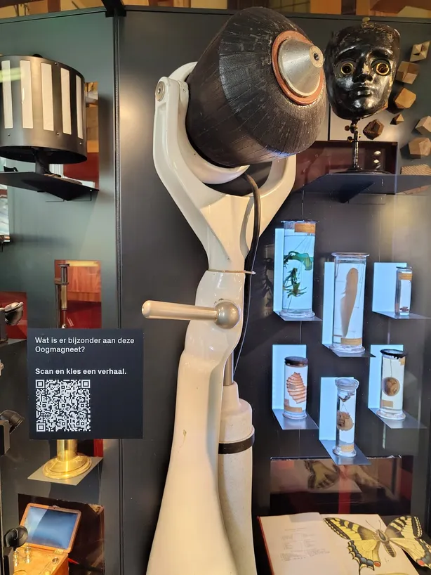 Oogmagneet in de vitrine, met daarnaast een QR-kaart met de vraag: wat is er bijzonder aan deze oogmagneet?